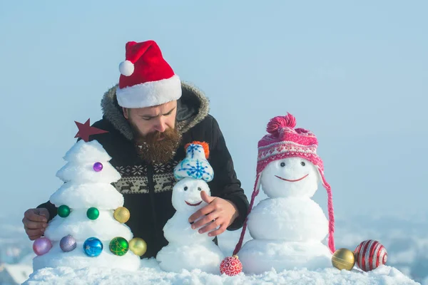 Schneemänner in Hüten und Schnee-Weihnachtsbaum am blauen Himmel — Stockfoto