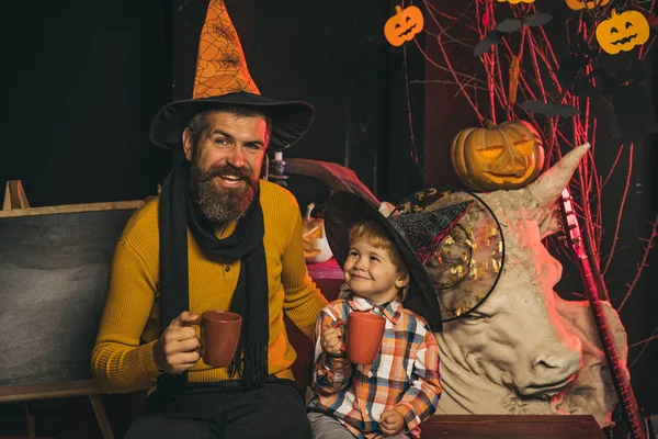 Halloween man and child in witch hat.