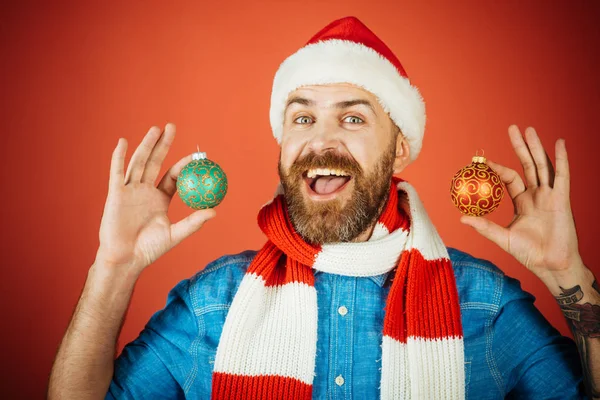 Kerst man houden xmas ballen op rode achtergrond — Stockfoto