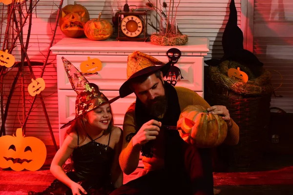 Kreator i mała czarownica w kapeluszach wyrzeźbić jack o lantern — Zdjęcie stockowe