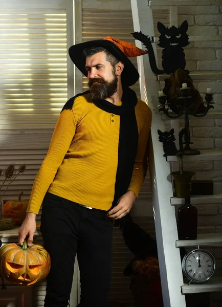 Magician and carved pumpkin. Man with beard holds jack lantern