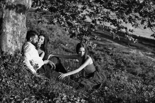 Homem barbudo e duas mulheres na grama — Fotografia de Stock