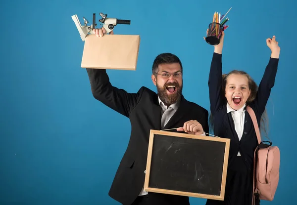 Kind und Lehrer halten Mikroskop, Tafel, Buch und Schreibwaren in der Hand — Stockfoto