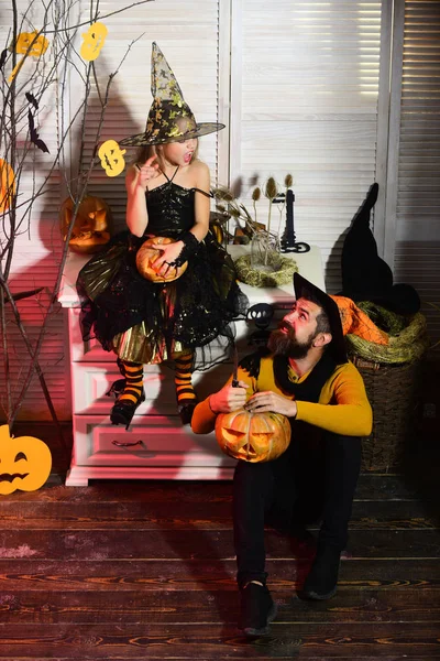 Sorcier et petite sorcière en chapeaux tiennent citrouilles — Photo