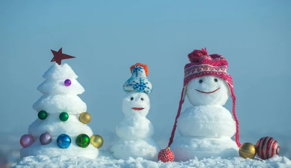 Muñecos de nieve con caras sonrientes en sombreros en el día de invierno — Foto de Stock