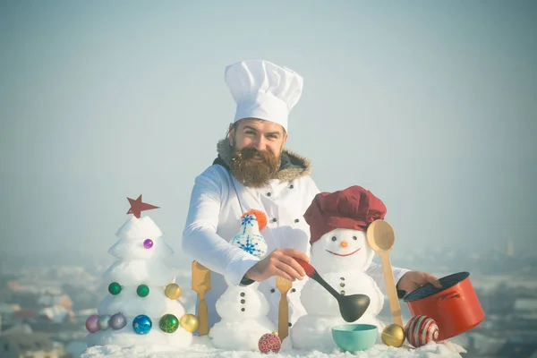 Mavi gökyüzü üzerinde mutlu aşçı, kardan adam ve kar xmas ağacı — Stok fotoğraf