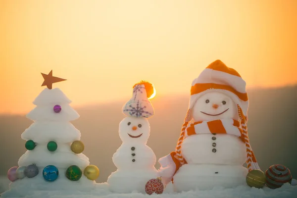 Sneeuwmannen met smileygezichten in hoeden op avond landschap — Stockfoto