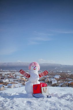 Pembe peruk ve mittens hediye paketi ile kardan adam.