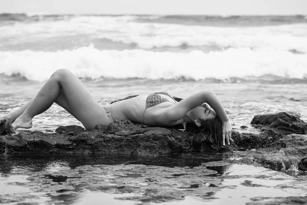 Bella ragazza in costume da bagno giallo sdraiata su rocce sulla spiaggia — Foto Stock