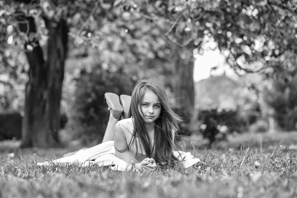 花びらと緑の草の上の少女 — ストック写真