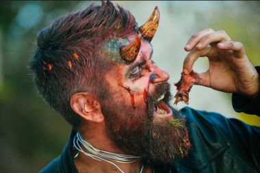 Cadılar Bayramı şeytan adam kafasına kanlı et yemek boynuzlarıyla