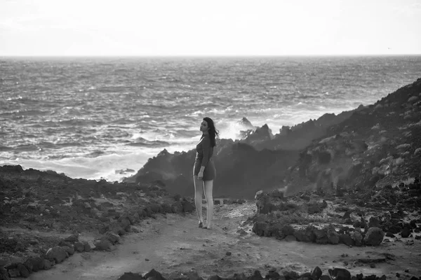 Hübsches Mädchen steht am felsigen Meeresstrand — Stockfoto