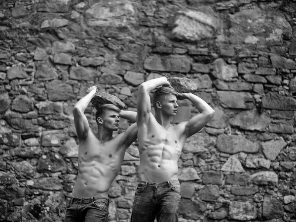 М'язисті близнюки на кам'яній стіні — стокове фото