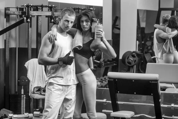 Muscoloso uomo e sexy ragazza a palestra trainer con bottiglia — Foto Stock