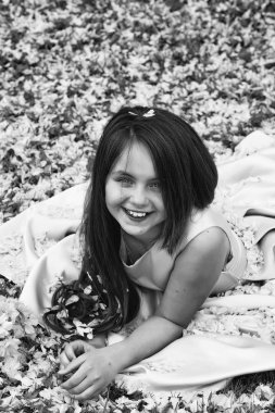 Yaprakları yeşil çimenlerin üzerinde küçük kız