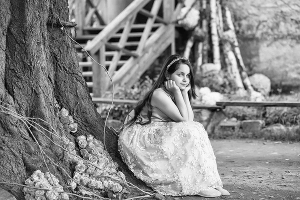 Menina perto de árvore e rosas amarelas — Fotografia de Stock