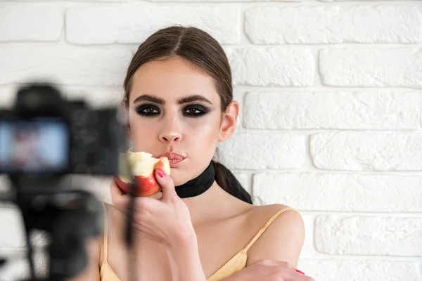 Mulher com olhos fumegantes comer maçã e olhar na câmera — Fotografia de Stock