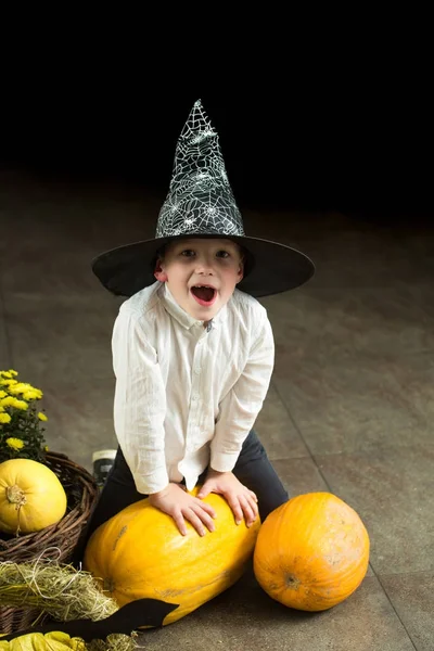 Halloween kid met oranje pompoen in heks hoed. — Stockfoto