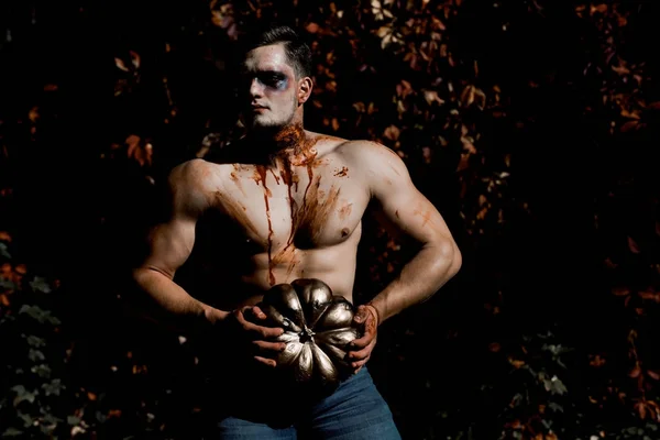 Halloween człowiek z zombie twarz i muskularne ciało posiada dyni — Zdjęcie stockowe