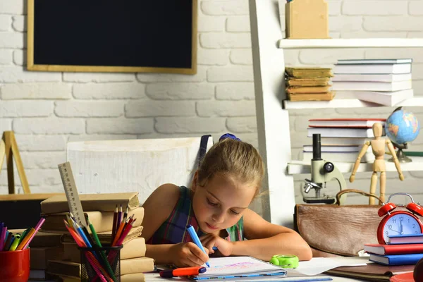 Дівчина з серйозним обличчям робить домашнє завдання на білому тлі стіни — стокове фото