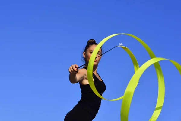 Mujer gimnasta en ropa deportiva negra con cinta verde . — Foto de Stock