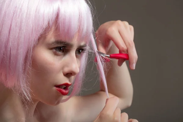 Vrouw met rode lippen in pruik op grijze achtergrond. — Stockfoto