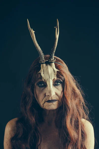 Halloween kvinna i svart med långa röda hår och makeup. — Stockfoto