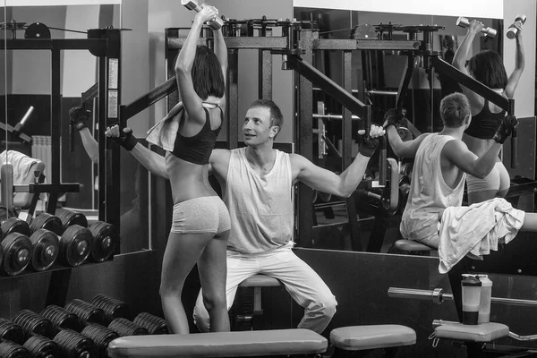 Musculoso homem e sexy menina no ginásio treinador com halteres — Fotografia de Stock