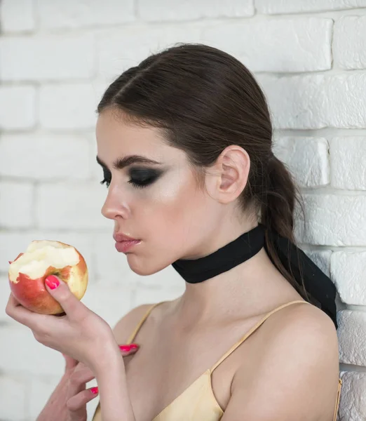 Mujer comer manzana en la pared de ladrillo blanco — Foto de Stock