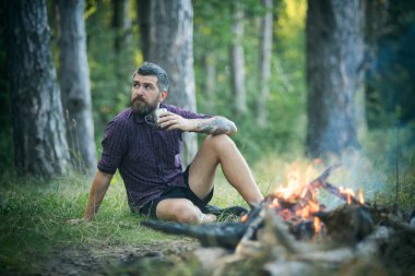 Hipster hiker kupa ile rahatla ormandaki şenlik ateşi