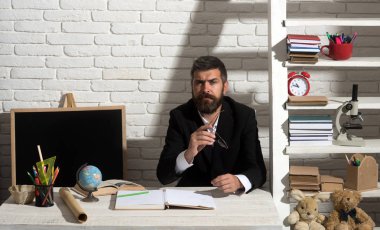 Profesör düşünceli yüz ifadesi ile masa başında oturur