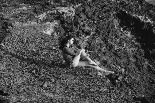 Menina bonita senta-se na superfície rochosa marrom — Fotografia de Stock