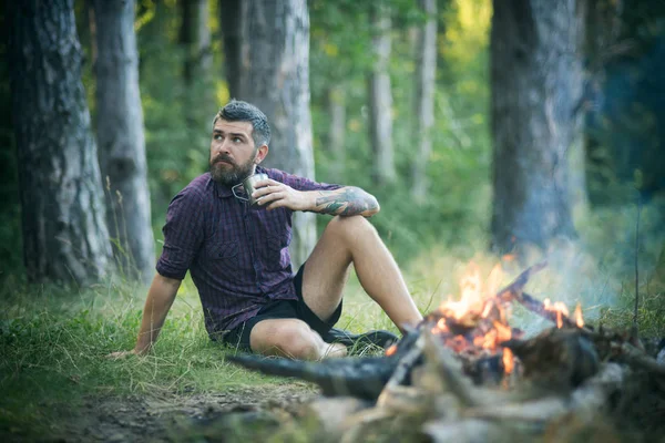 Hipster-Wanderer mit Becher entspannen am Lagerfeuer im Wald — Stockfoto