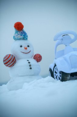 Gri gökyüzü kış gününde kardan adam ve oyuncak araba