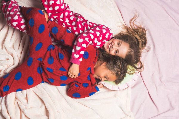 Children in pajamas happy smile in bed, top view
