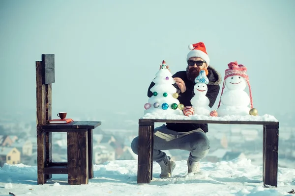 Muž v brýlích zdobení sněhové vánoční strom na modré obloze — Stock fotografie