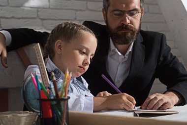 Adam ve çocuk okul malzemeleri ile masa başında oturmak