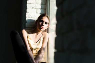 Kız dinlenme pencere pervazına beyaz tuğla duvar üzerinde