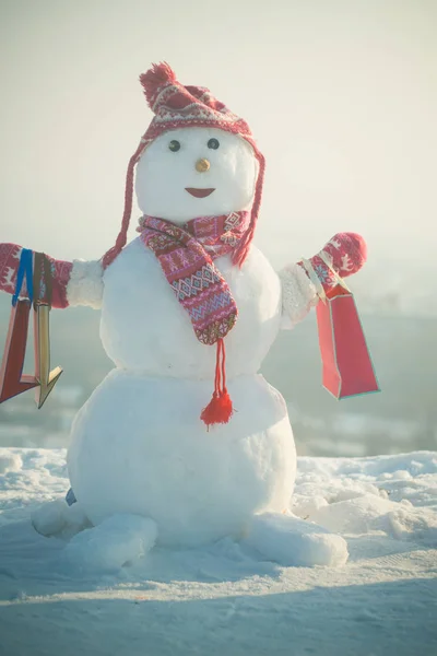 Muñeco de nieve con sombrero, mitones y bufanda con paquete de regalo . —  Fotos de Stock