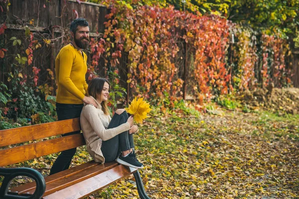 Man and woman with yellow tree leaves.