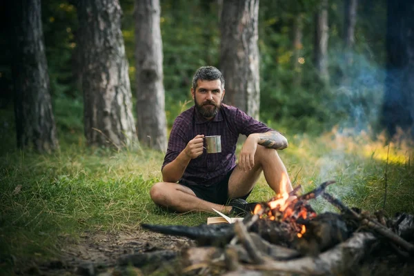 Хіпстерський піший турист з чашкою відпочиньте на багатті в лісі — стокове фото