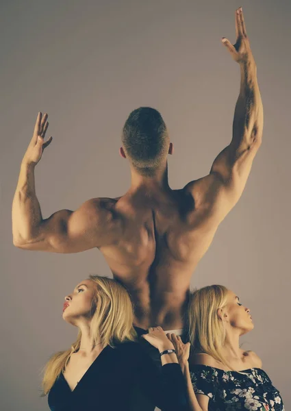 Homem fisiculturista com costas musculares levantar mãos e meninas — Fotografia de Stock
