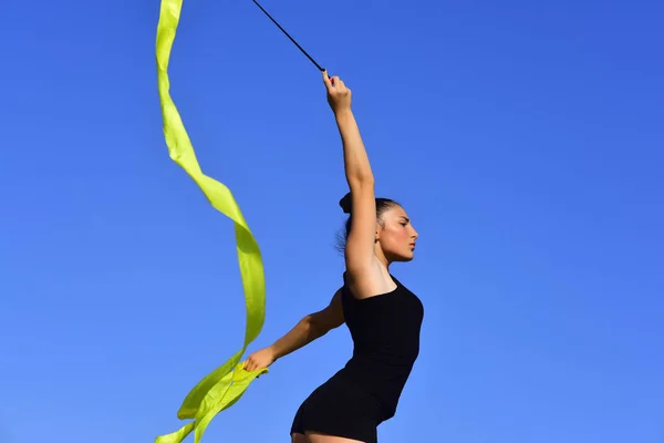 Mujer gimnasta en ropa deportiva negra con cinta verde . — Foto de Stock