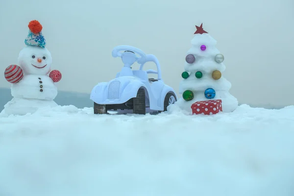 Sněhulák a hračka auto na zasněžené pozadí — Stock fotografie