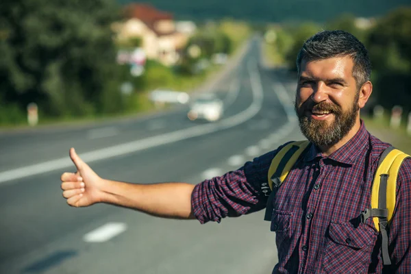 Hombre con mochila feliz autostop en el camino — Foto de Stock