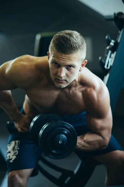 Bodybuilder-Mann baut Handmuskeln mit Hantel im Fitnessstudio auf — Stockfoto