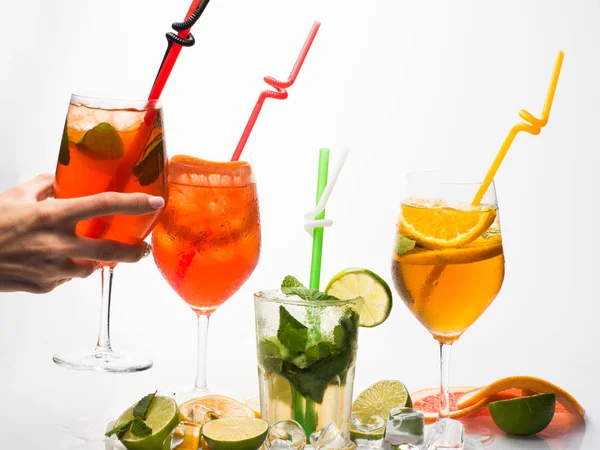 Cóctel colorido bebida con rodajas de frutas y la mano de la mujer — Foto de Stock