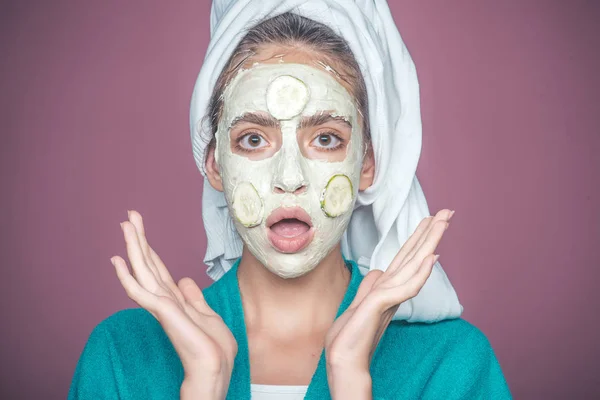 Flicka med gurka mask på förvånade ansikte på violett bakgrund — Stockfoto