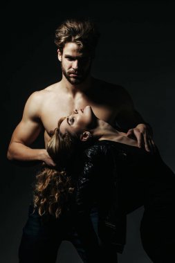 Gövdesi kaslı bir adam kadını uzun saçlarıyla tutuyor.