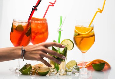 Alkollü içecek ve meyve kadın el ile restoranda. Meyve dilim ve kokteyl cam bar. Parti ve yaz tatil. Mojito beyaz zemin üzerine izole kokteyl. İçecek ve gıda.